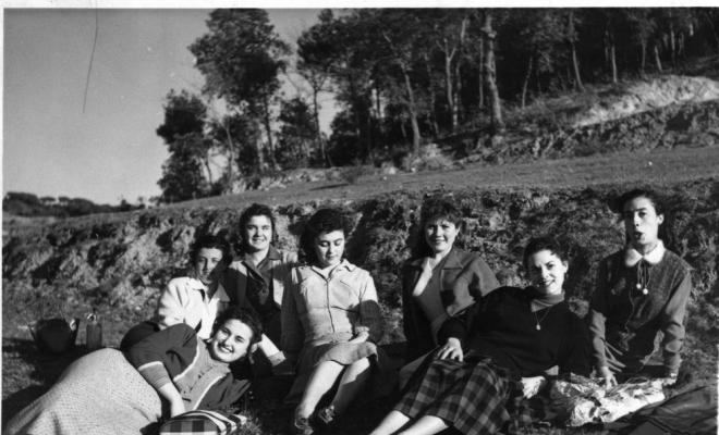 Set alumnes de costura de Teresa Torres assegudes a terra a la zona del Pi de l'Indià