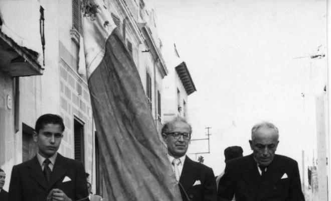 Tres homes amb una bandera durant la processó de Corpus