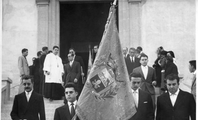 Homes amb la bandera de l'Ajuntament baixant les escales de l'església per Corpus