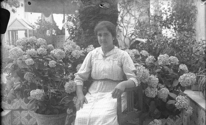 Retrat d'una dona asseguda en una cadira en un jardí
