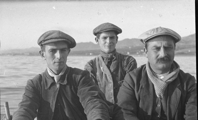 Tres homes en un pati remant cap a la pesca del calamar