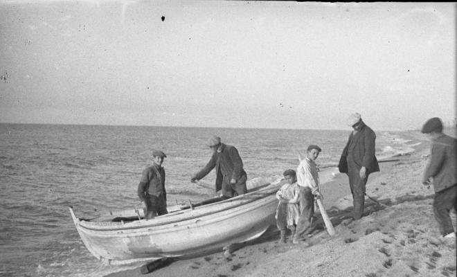 Homes al voltant d'una barca varada a la platja a la vora del mar