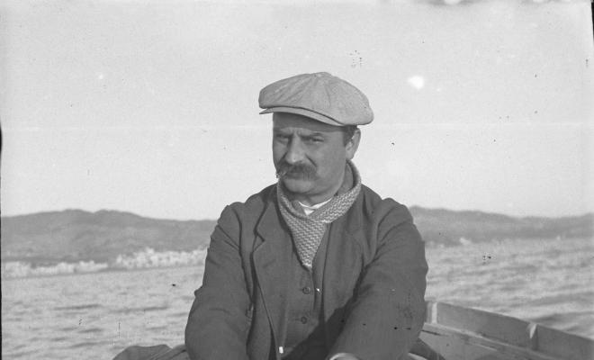 Home amb bigoti remant en una barca