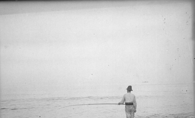 Home sobre una cadira pescant a la platja