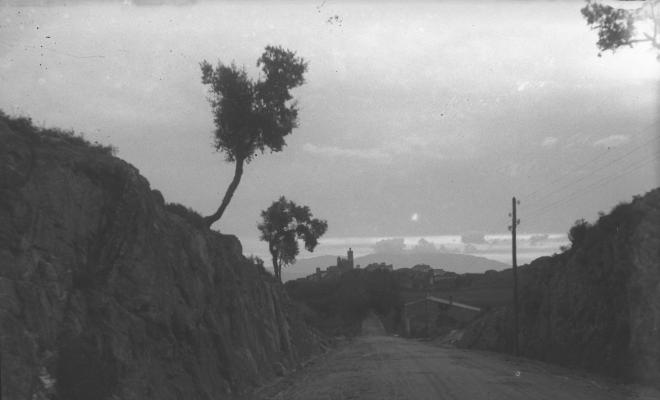Camí de sorra amb vistes d'un poble al fons