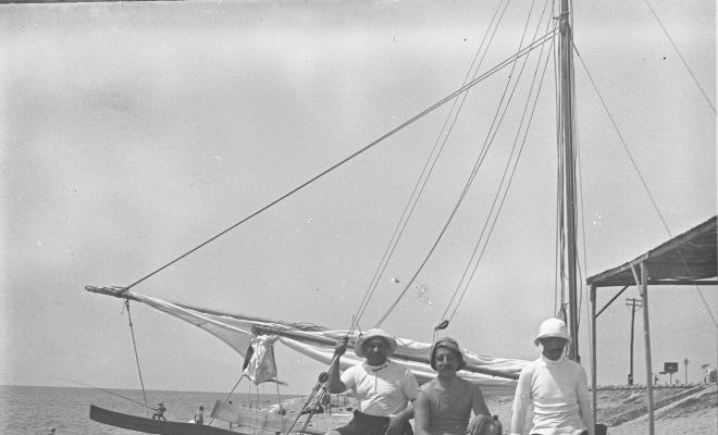 Tres homes asseguts sobre un pati de vela
