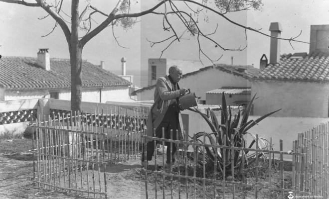 Un home regant una planta al carrer de la Caterra?