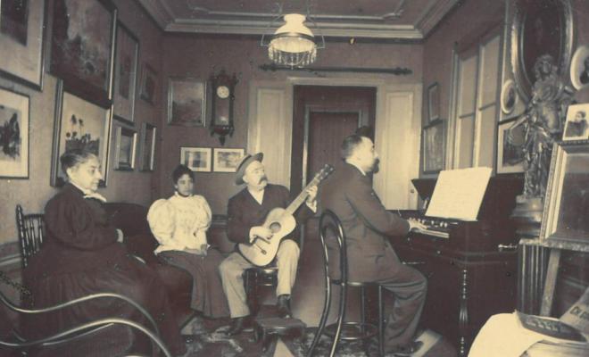 Interior d'una casa amb homes tocant música i dones escoltant