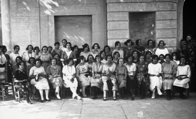Grup de dones assegudes davant l'edifici de l'Ajuntament