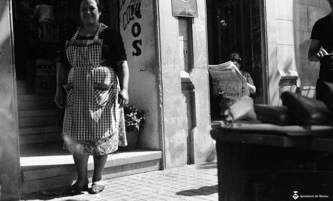 Dona sortint d'una botiga i altra llegint el diari