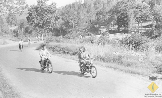 Grup de jove en bicicleta i motocicleta per l'actual carretera BV-2421 el dia de la visita del bisbe de Barcelona