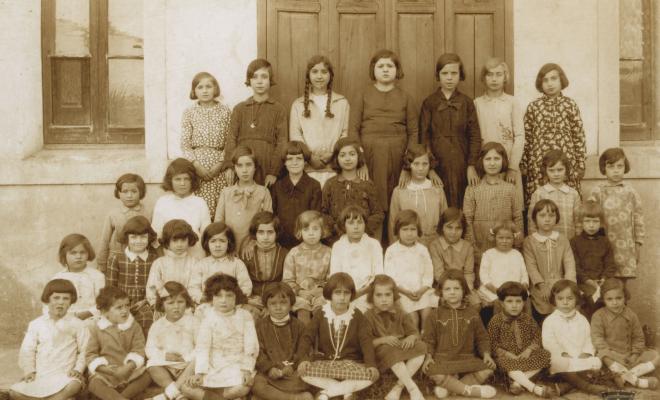 Grup escolar femení davant de la porta de l'escola