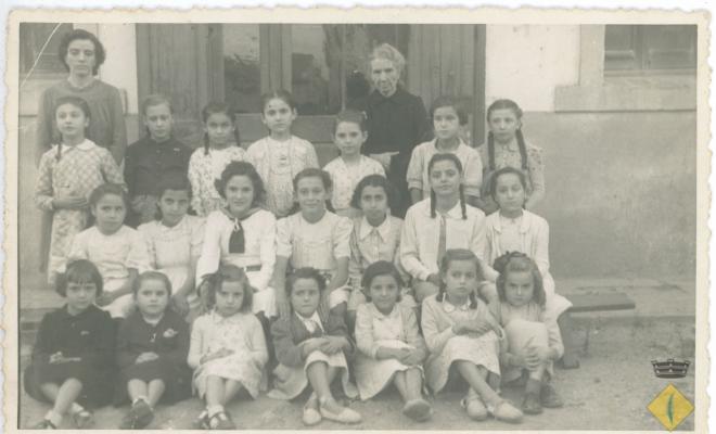 Retrat del grup escolar de nenes davant la porta de l'escola