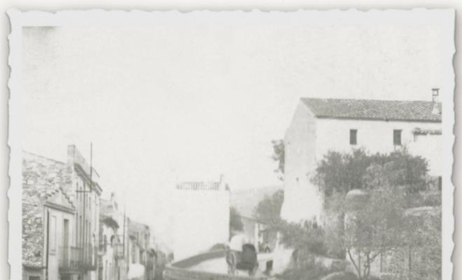 Vista del creuament entre el carrer Sant Isidre i l'avinguda Catalunya mentre una tartana passa per la corba de l'església