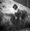 Dona retratada, mostrant una flor, al pati del fotògraf.